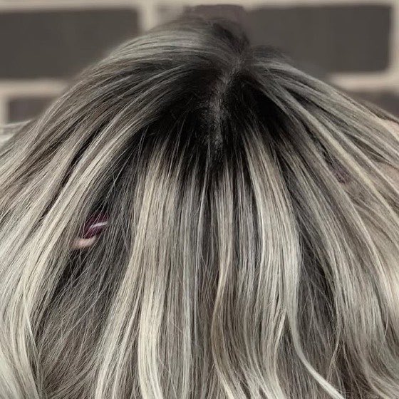 Ash blonde hair with soft silver highlights and a blended dark root, styled straight.