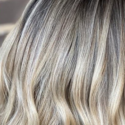Soft blonde balayage with a blended shadow root and loose waves.